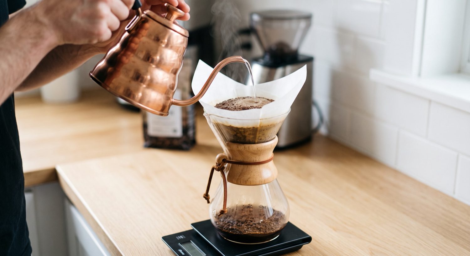 Hot water poured from a copper gooseneck kettle into a Chemex on a scale.
